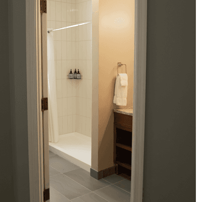 Modern guest bathroom with walk in shower behind glass door beside vanity and towel rack at La Tourelle Hotel and Spa
