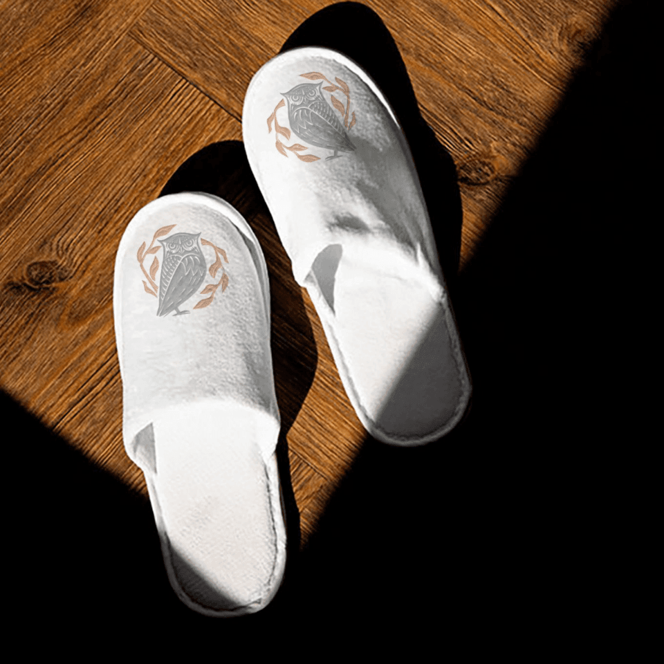 Close-up of white slippers featuring hotel logo at Hotel Brookmere