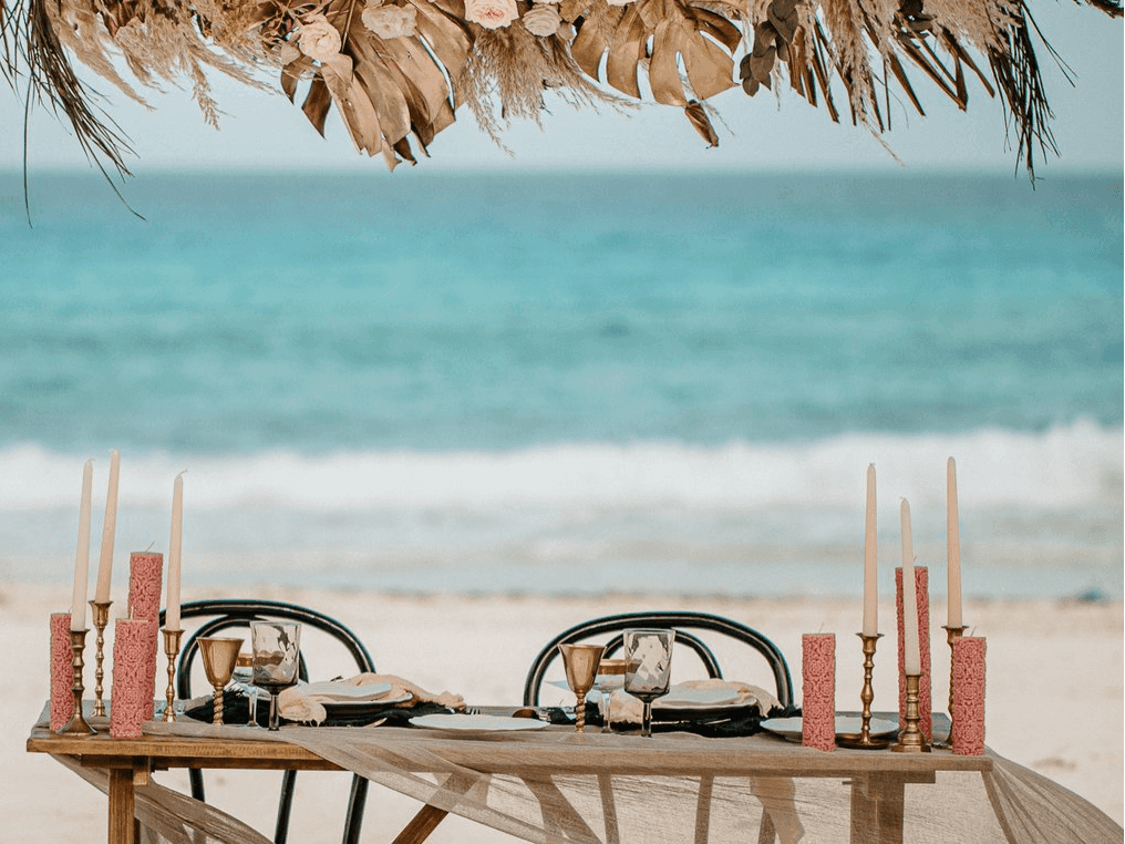 Montaje de cena a la luz de las velas en la playa en Grand Fiesta Americana