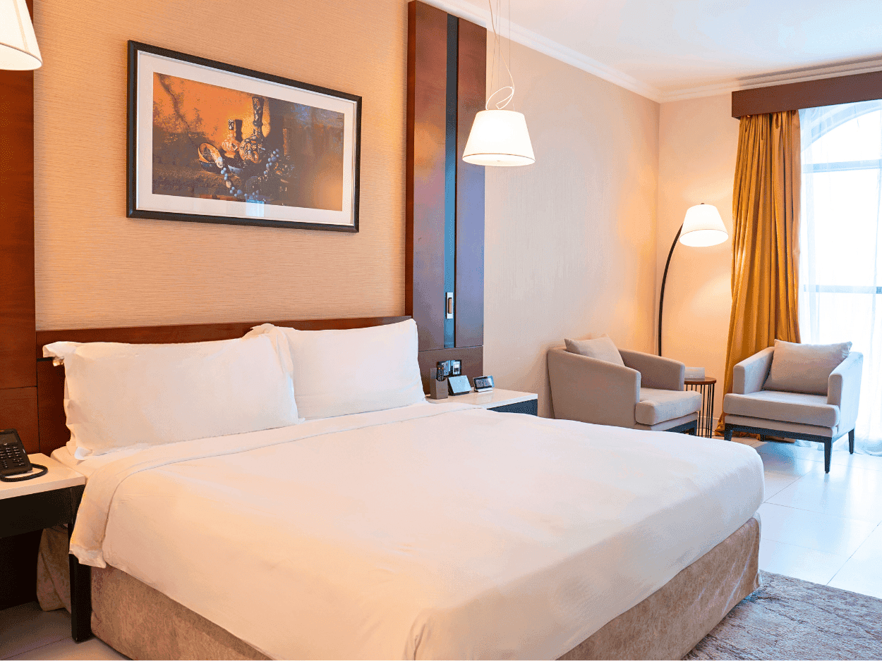Deluxe King Room with a large bed, chairs, and a window at Asma Hotel in Dubai.