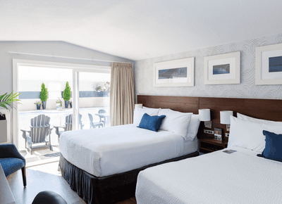 Two double beds with dark headboards inside a spacious guest room beside patio doors to the pool area at Rodd Moncton