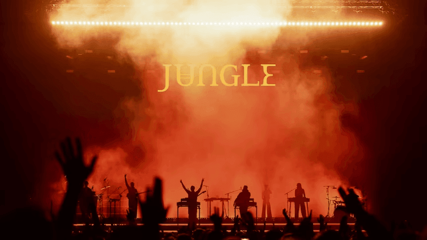 Performers on stage with Jungle World Tour - 2027 text and audience raising hands.