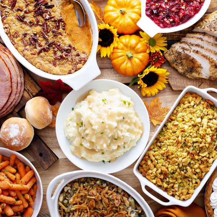 thanksgiving table with turkey, ham, mashed potatoes, stuffing, pie, & fall decor