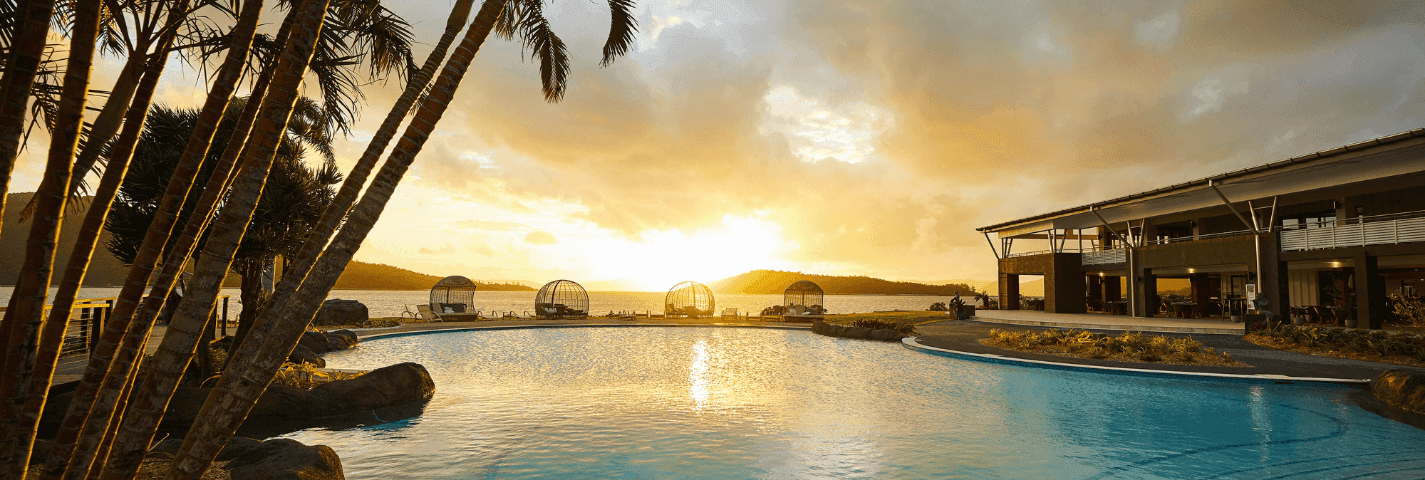 Coconut trees and pool at sunset at Daydream Island Resort