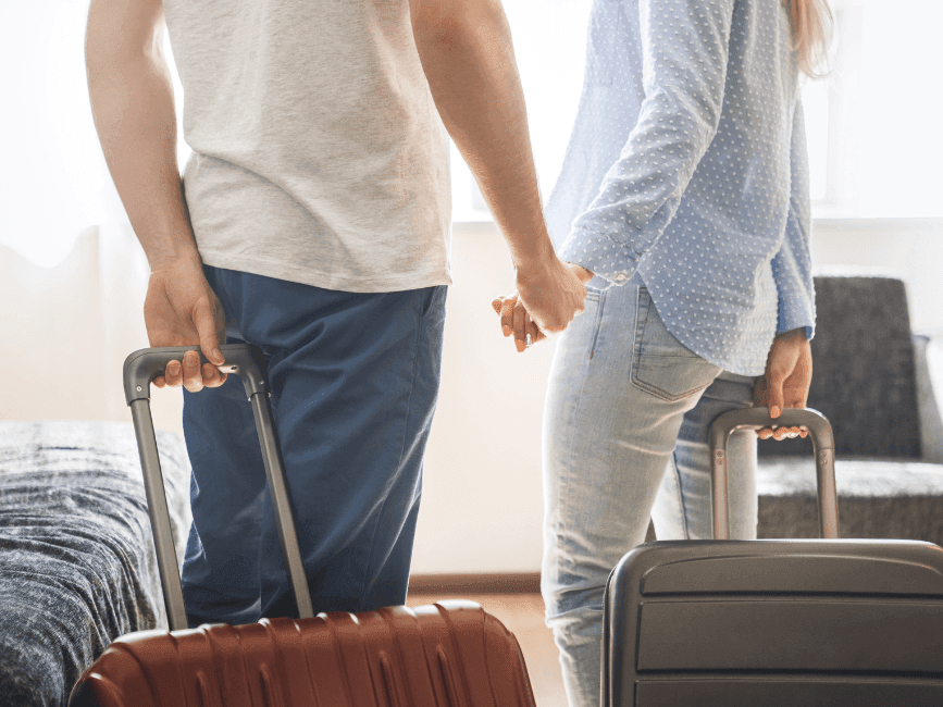 A couple holding luggage's in a Bedroom at The Exeter Inn