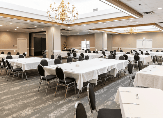 Banquet tables set with white tablecloths under chandeliers in a large event space at Rodd Hotels & Resorts