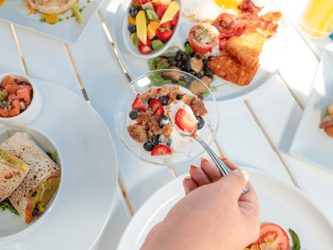 Hand reaching for a bowl of yogurt and berries at Amsterdam Manor Beach Resort