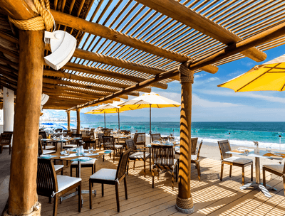 Outdoor dining area of Sunset Restaurant with umbrellas and ocean view at Buenaventura Grand Hotel and Spa