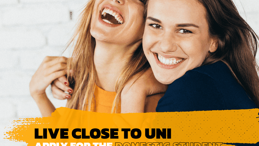 Two female students embracing against a white brick wall in a promotional image for UniLodge Park Avenue.