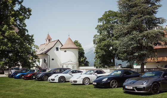 A row of cars parked in the garden of Imlauer Schloss Hotel