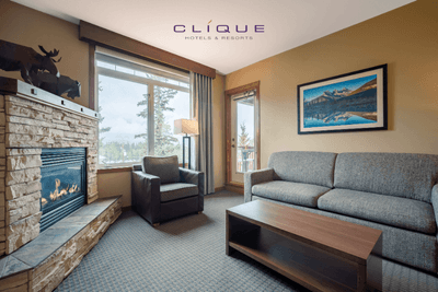 Living room in a suite at Falcon Crest Lodge features a comfortable sofa, an armchair by the window, a stone fireplace