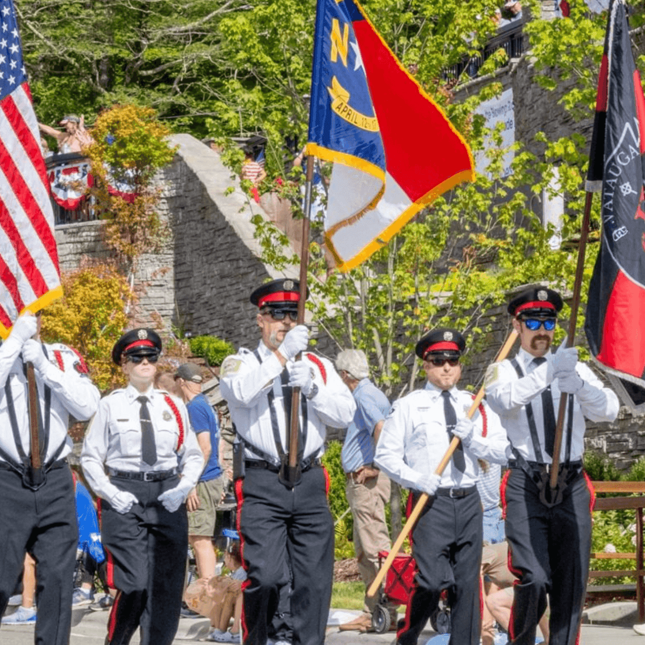 Uniformed officers march in a parade holding the American, North Carolina, and Katauga flags.