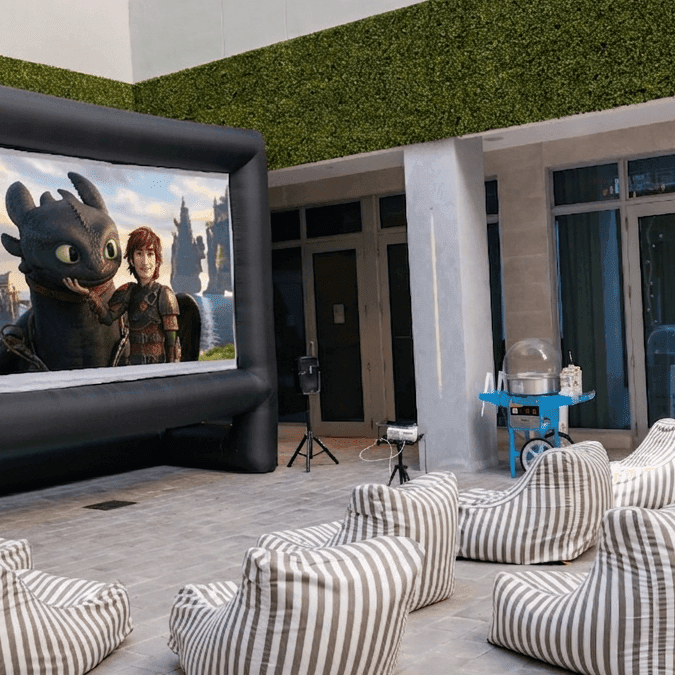 An outdoor movie setup with an inflatable screen and bean bags.