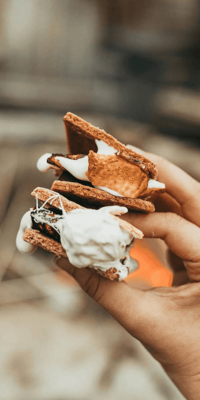 Hand holding two toasted marshmallows and chocolate graham crackers s\'mores outdoors at La Tourelle Hotel and Spa