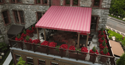 Dining area on terrace with red flower plants at The Abbey Inn