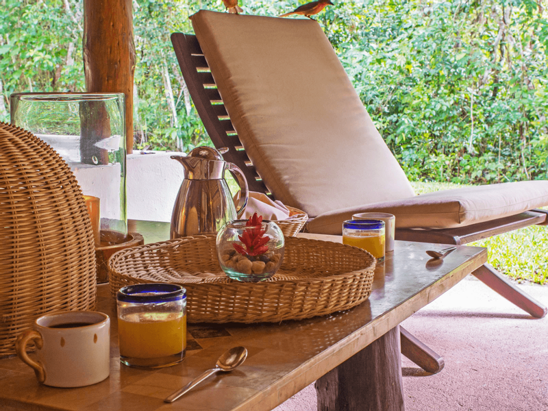 Coffee & fresh juice served by an outdoor lounge area with lush greenery at The Explorean Kohunlich