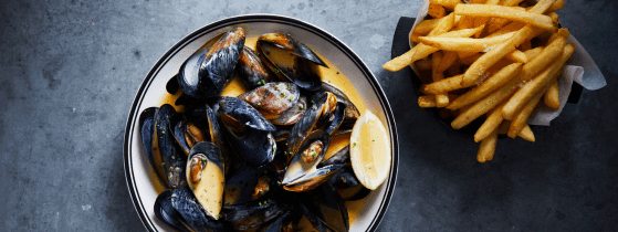 Delicious bowl of steamed mussels in creamy sauce with crispy fries at Steak & Oyster Co. by Sean Connolly, Novotel Sydney