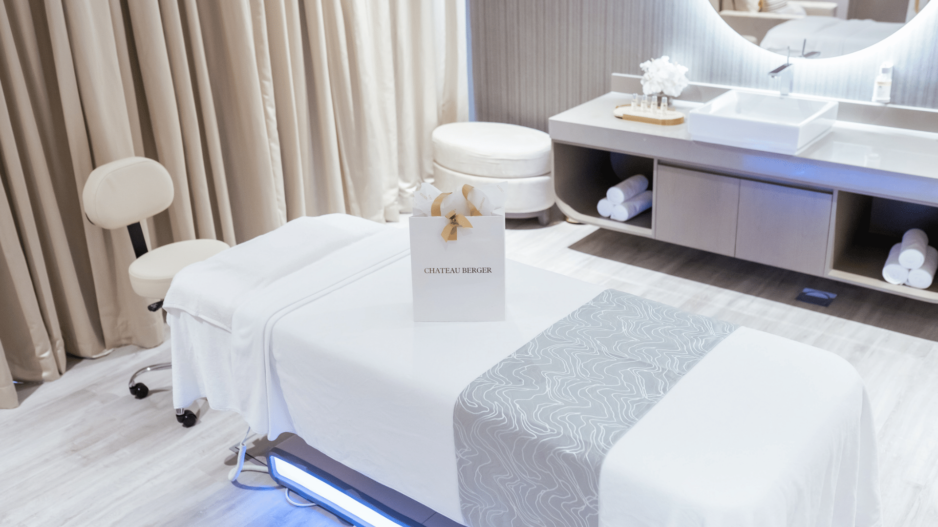Bright and clean spa treatment room with a massage bed, modern sink area, and a gift bag at Paramount Hotel Midtown