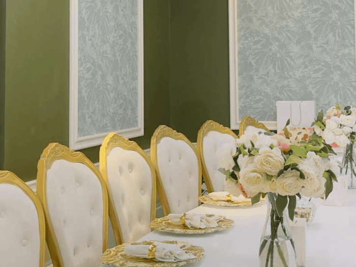 Elegant gold-trimmed chairs by a long table with white flowers, in Emerald Room at Warwick Hotels & Resort