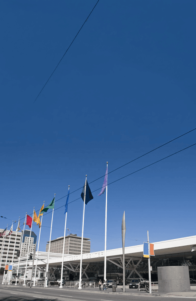 Row of flags in front of a modern building under a clear blue sky at Pickwick San Francisco