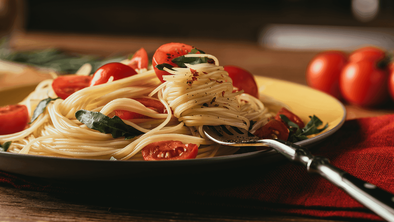 Plato de pasta con tomates cherry y albahaca fresca sobre una mesa de madera en Trattoria Pomodoro en Hacienda del Mar Los Cabos