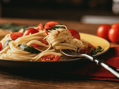 Plato de pasta con tomates cherry y albahaca fresca sobre una mesa de madera en Trattoria Pomodoro en Hacienda del Mar Los Cabos
