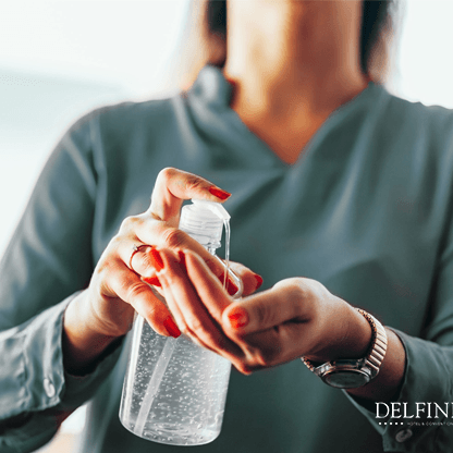 Lady taking sanitizer from a sanitizer bottle at Delfines Hotel