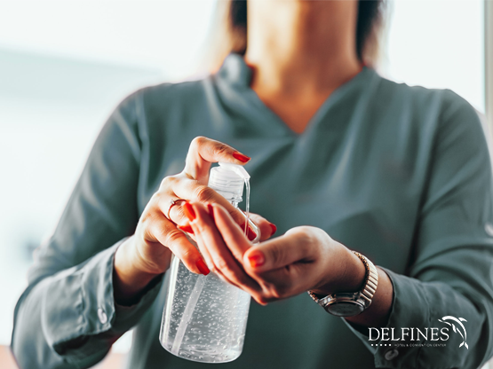 Lady taking sanitizer from a sanitizer bottle at Delfines Hotel