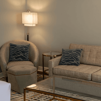 Cozy corner seating with plush sofa beside round armchair, and floor lamp on patterned rug at La Tourelle Hotel and Spa