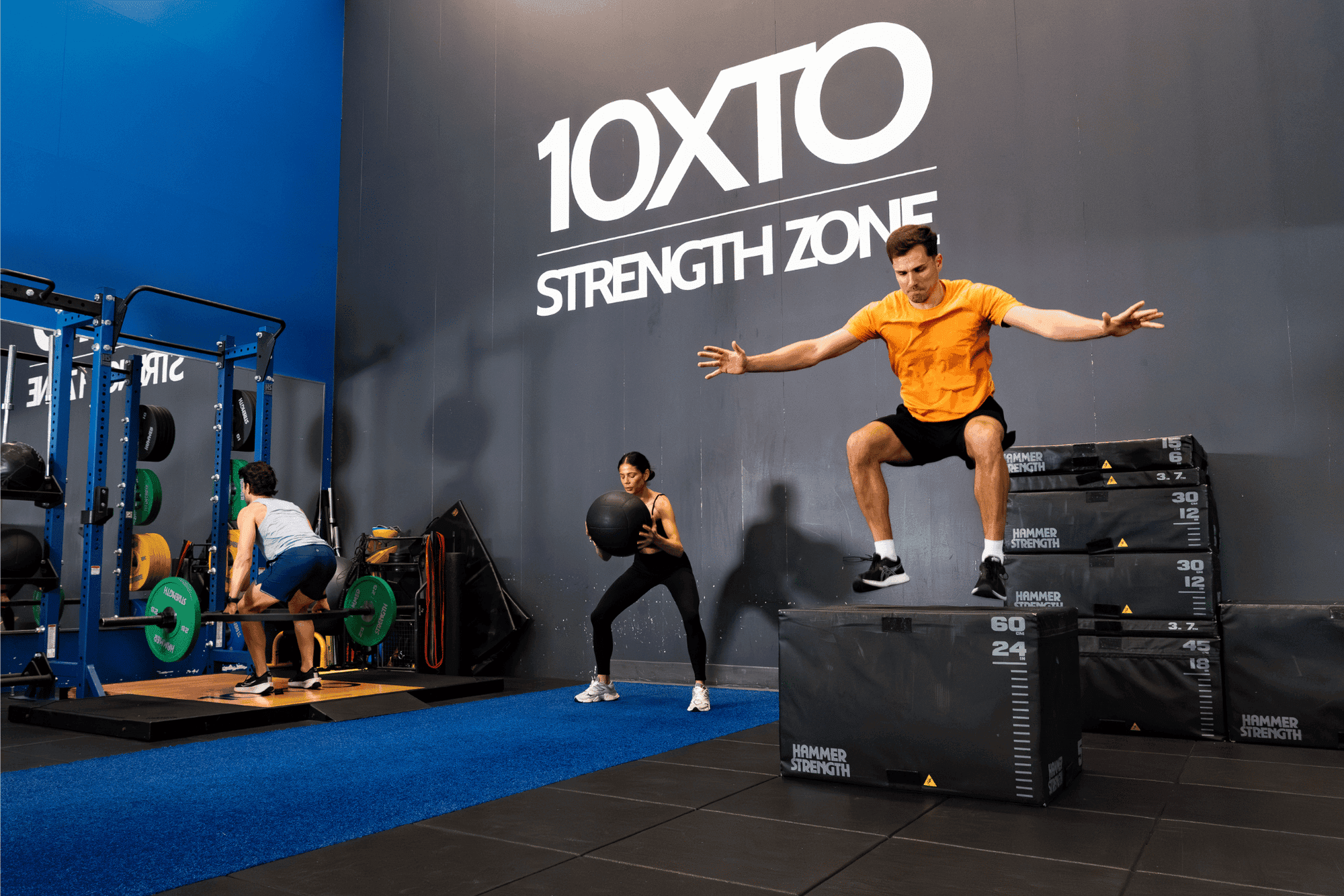 Guests training with weights and plyometric boxes under the 10XTO Strength Zone sign in the gym at Hotel X Toronto