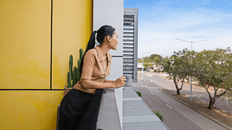Woman enjoying a balcony view with cactus and urban street at StudentLiving Darwin.