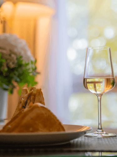 Glass filled with white wine on a table next to a sandwich in a room at Warwick Reine Astrid - Lyon