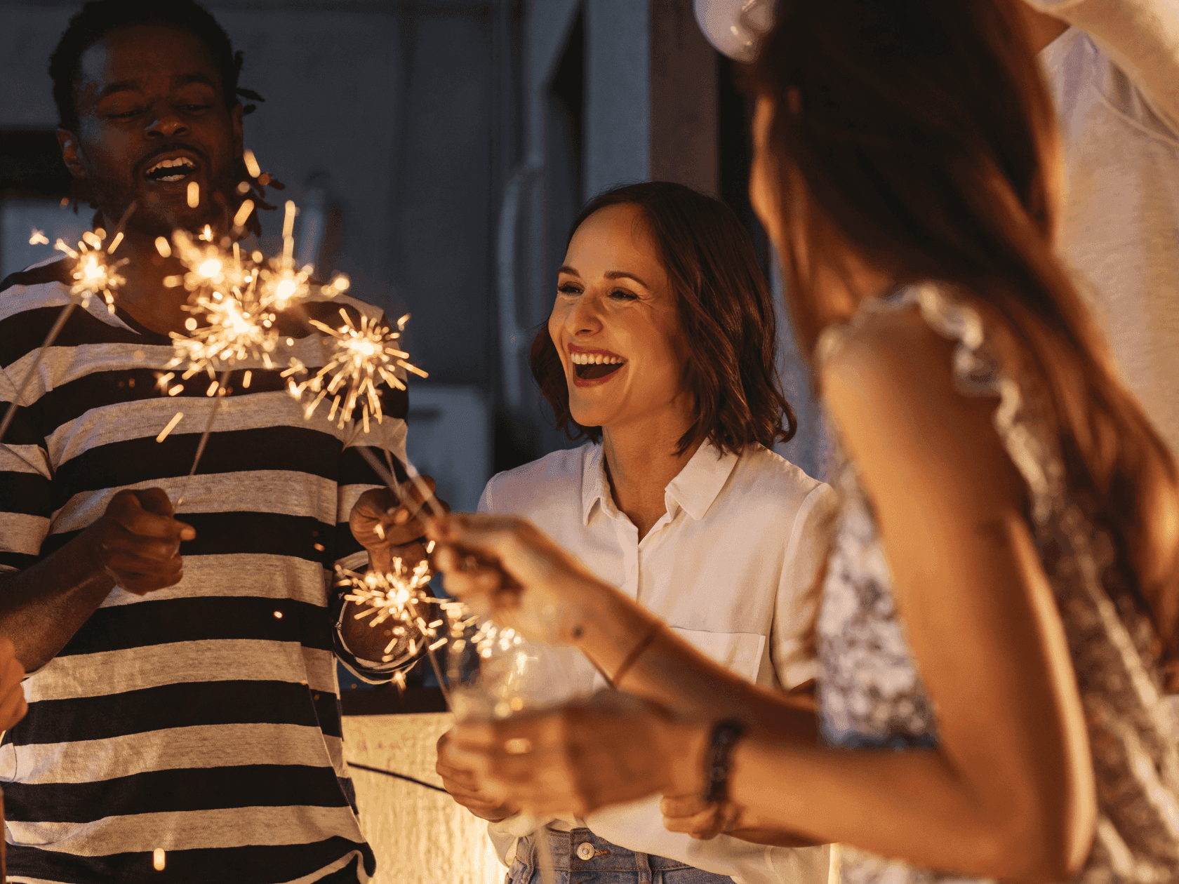 People celebrating with sparklers and champagne glasses in a festive atmosphere.