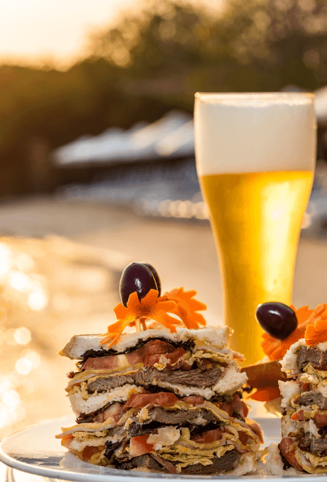 Close-up of meat sandwiches and a glass of beer served at Hotel Isla Del Encanto
