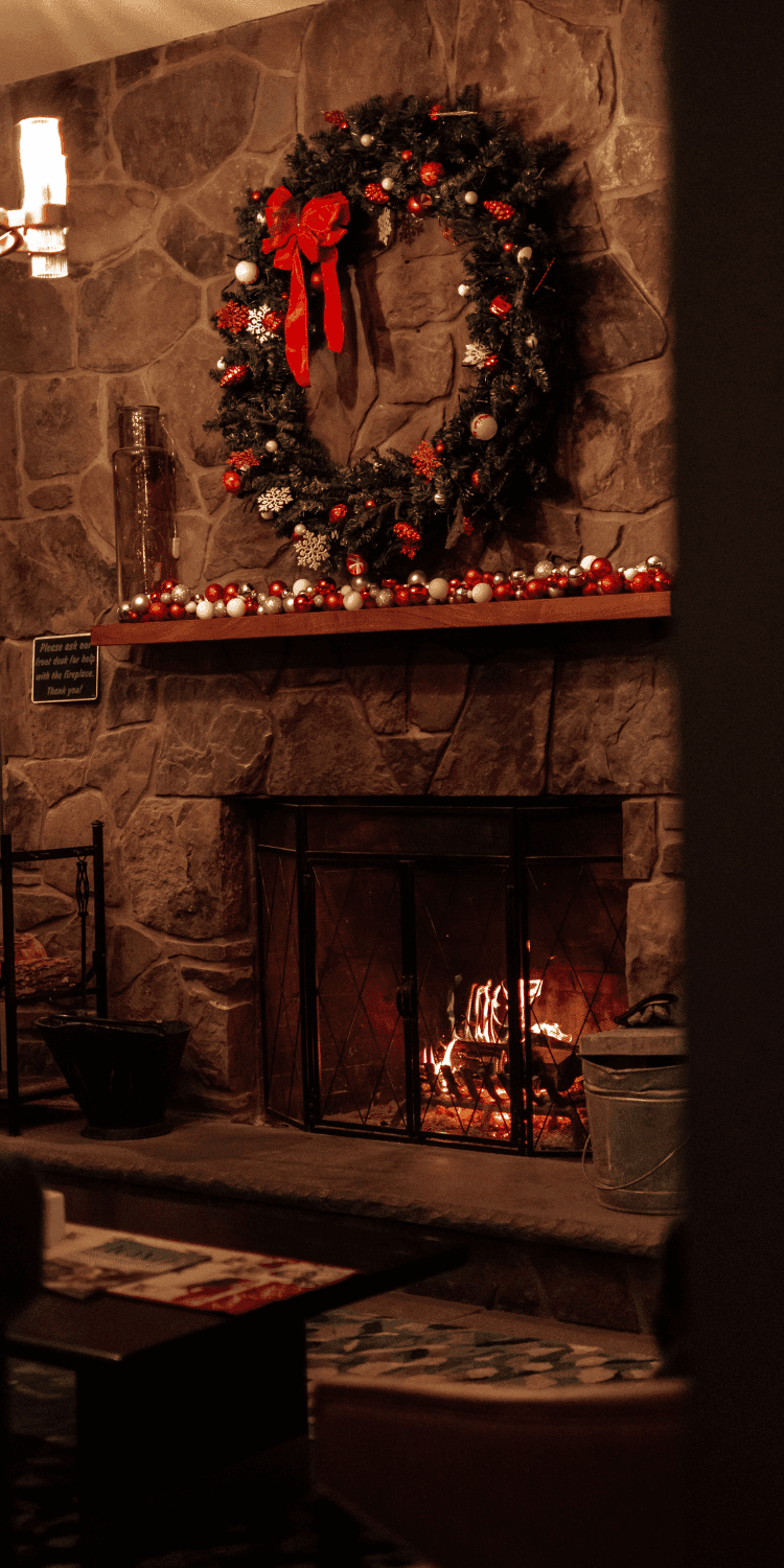 Christmas wreath and ornaments decorate a stone mantel above a lit fireplace in the lobby at La Tourelle Inn and Spa