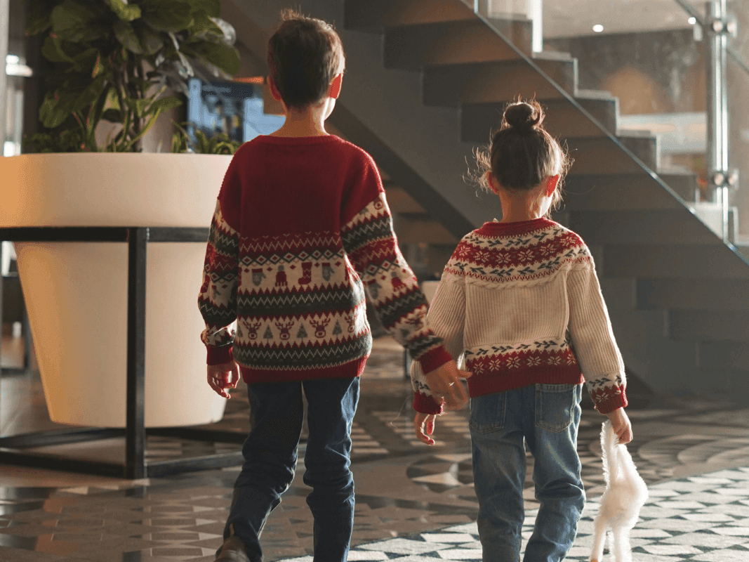 2 kids walking in the lobby with Holiday sweaters on