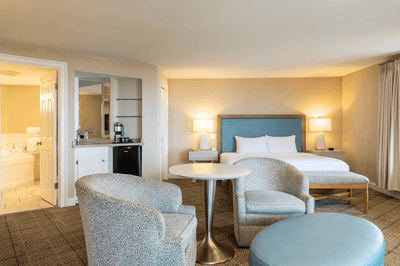 Spacious guest room with a bed, sitting area, table, kitchenette, and bathroom at Anchorage By The Sea