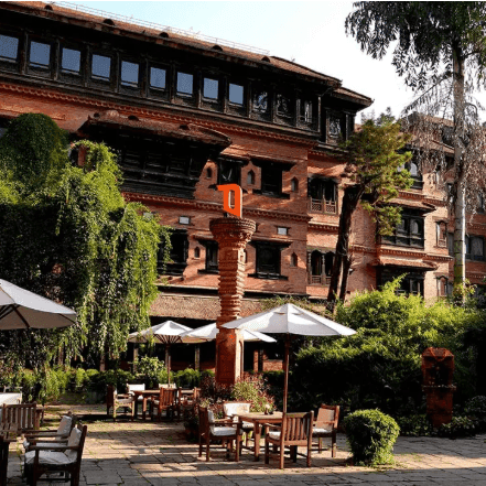 Exterior view of the hotel and outdoor dining area with patio umbrellas at The Dwarika’s Hotels and Resorts