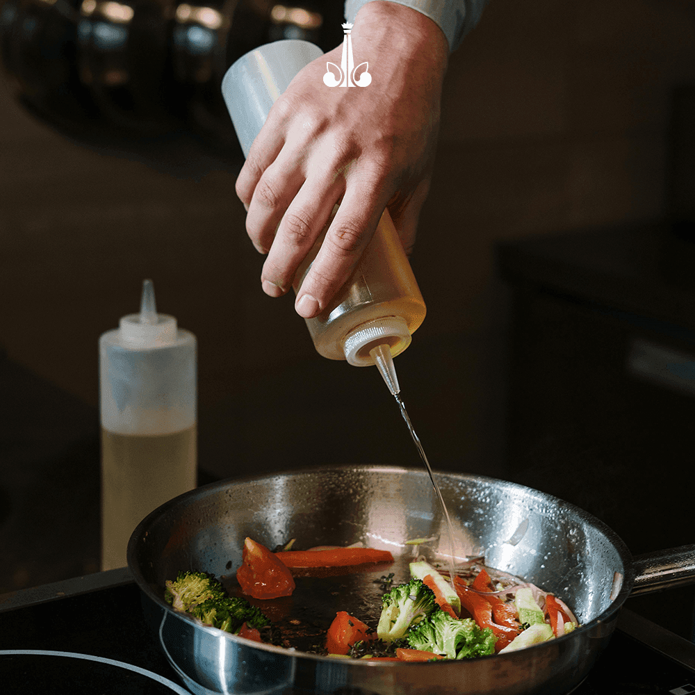 Chef cooking fresh vegetables in a pan at Marquis Los Cabos Resort
