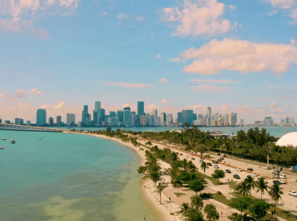 A wide view of a beach with a city skyline in the background.