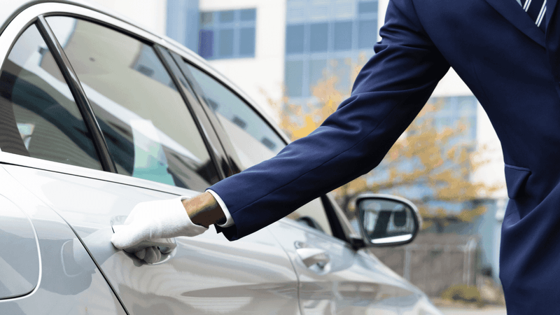 Close-up of a taxi driver opening the door for Valet parking service at Warwick Le Crystal