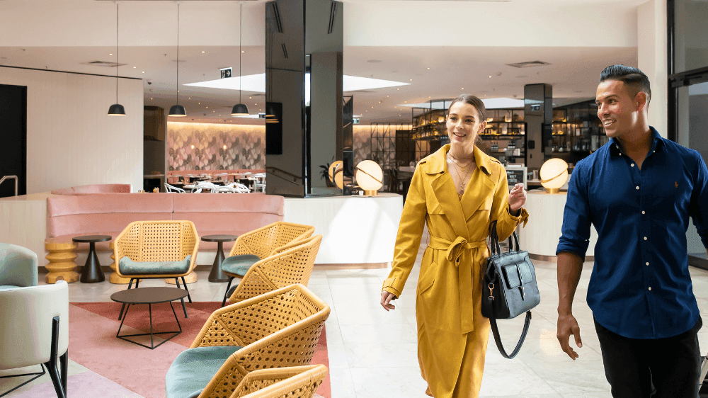 Smiling couple with luggage walking through the modern lobby at Novotel Sydney International Airport
