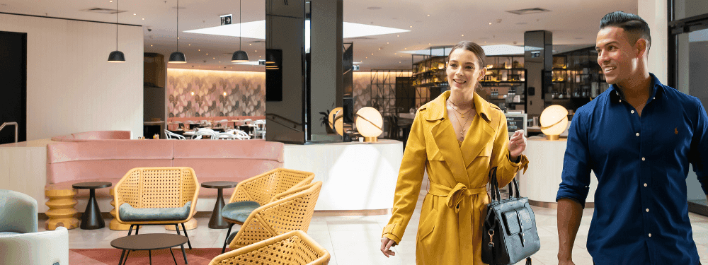 Smiling couple with luggage walking through the modern lobby at Novotel Sydney International Airport