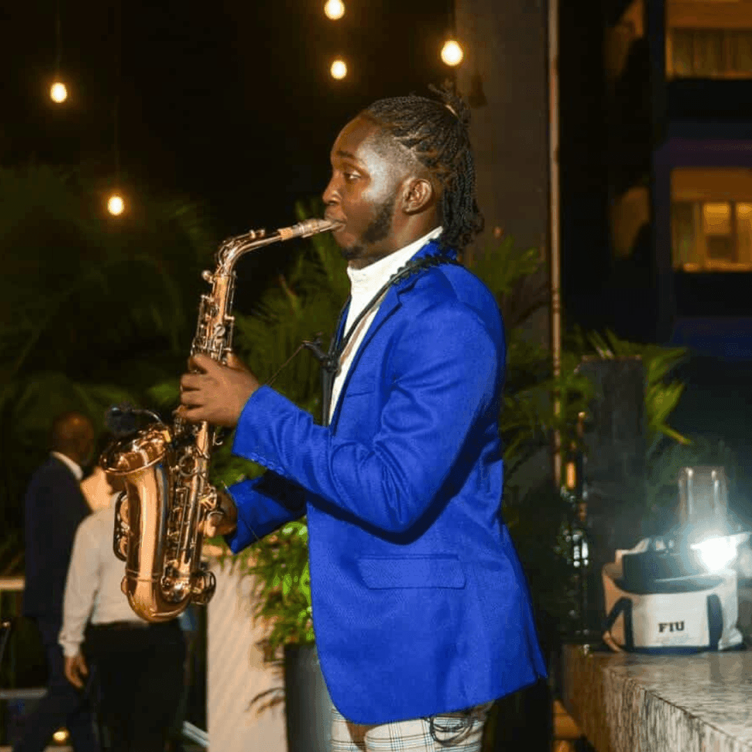 Saxophonist in vibrant blue suit performing outdoors under string lights during Live Music Fridays.