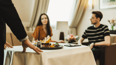 Waiter serving a meal to a couple in a restaurant at Polonia Palace Hotel