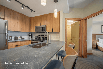 Modern kitchen in a suite at Falcon Crest Lodge features wooden cabinets, stainless steel appliances, a breakfast bar