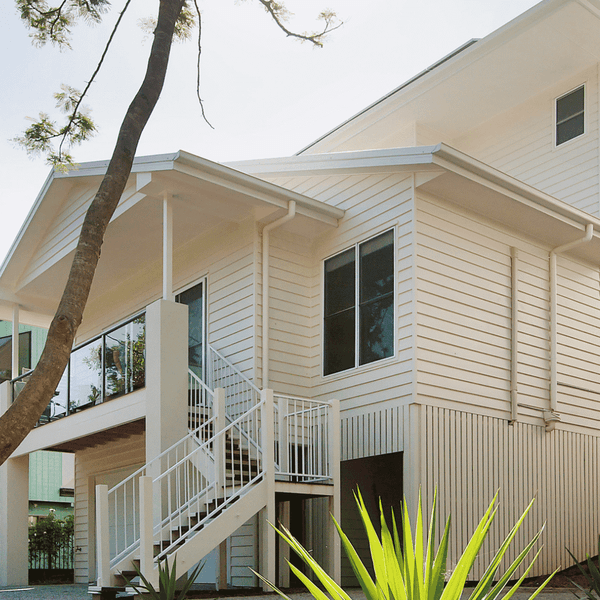 Modern white two-story student accommodation building with external staircase and tropical landscaping at Twelfth Avenue