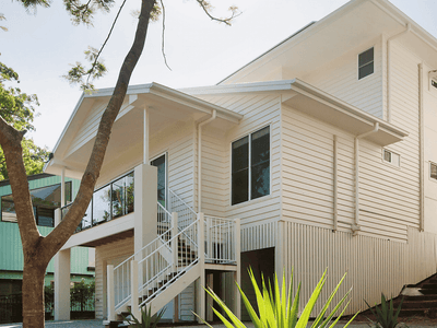 Modern white two-story student accommodation building with external staircase and tropical landscaping at Twelfth Avenue