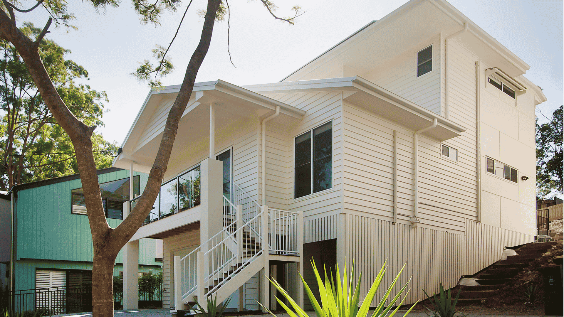 Modern white two-story student accommodation building with external staircase and tropical landscaping at Twelfth Avenue
