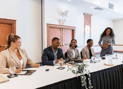 Business guests smiling and networking around a conference table during a meeting at Rodd Crowbush Golf & Beach Resort